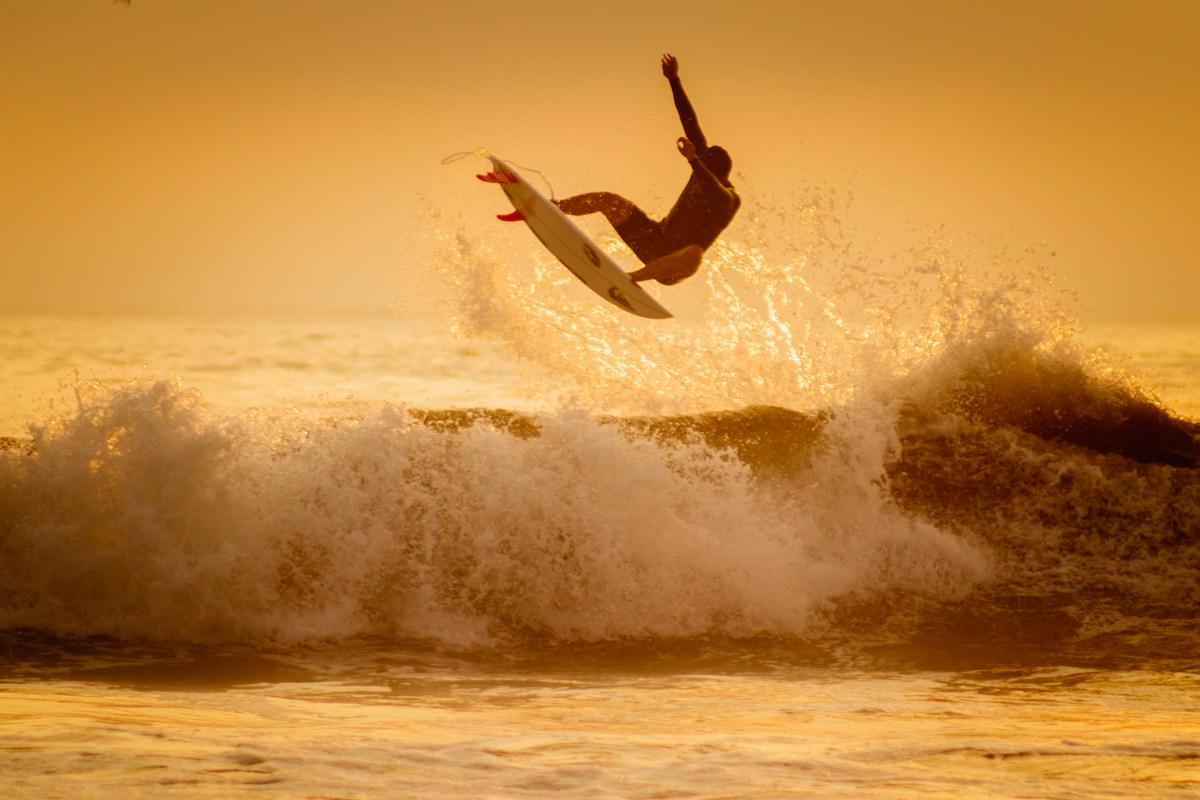 Surfer launching an aerial on a powerful Pacific wave at golden hour, San Antonio, Peru