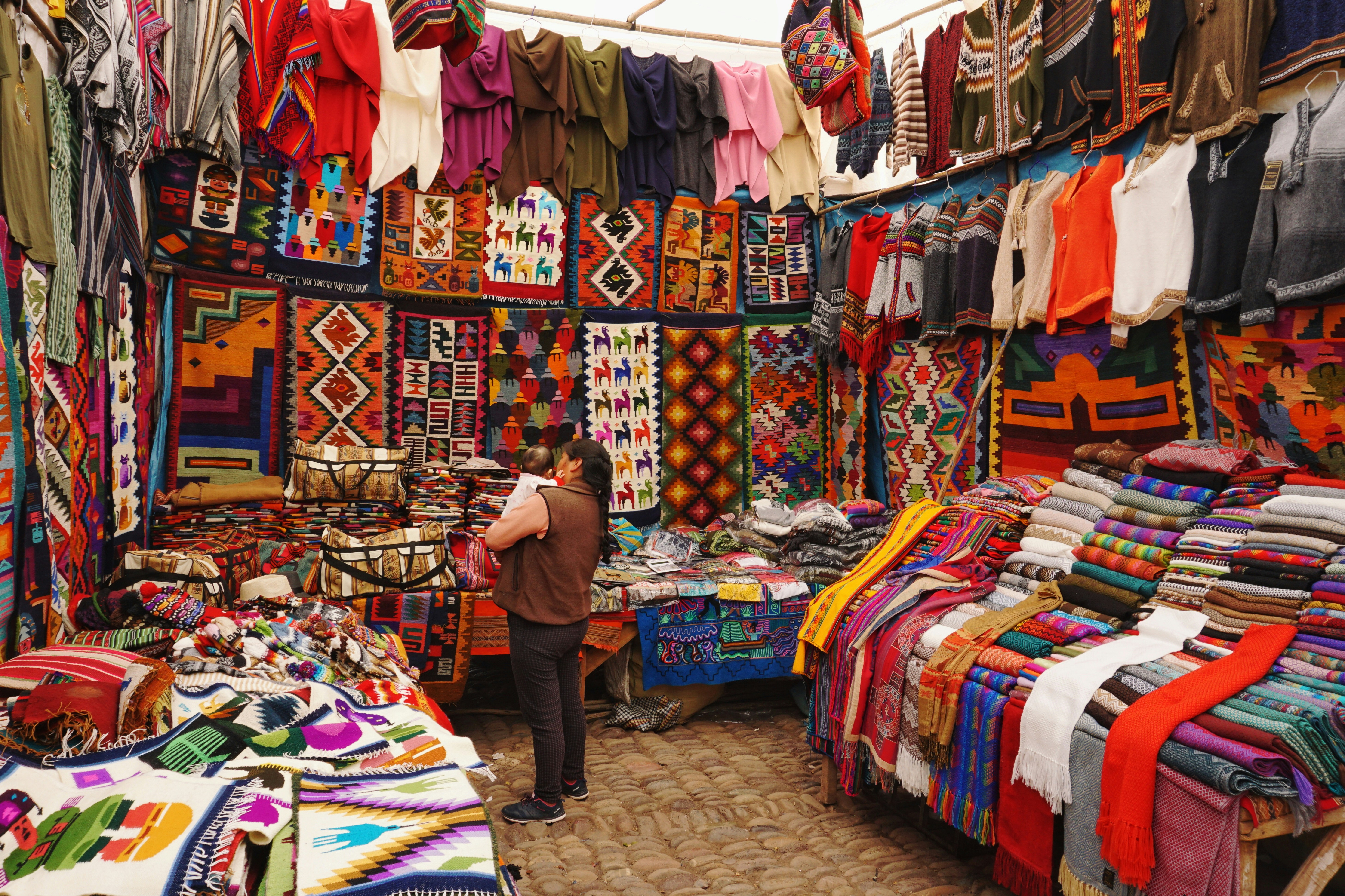 Colourful handwoven textiles and tapestries hanging in an artisan market stall in Peru