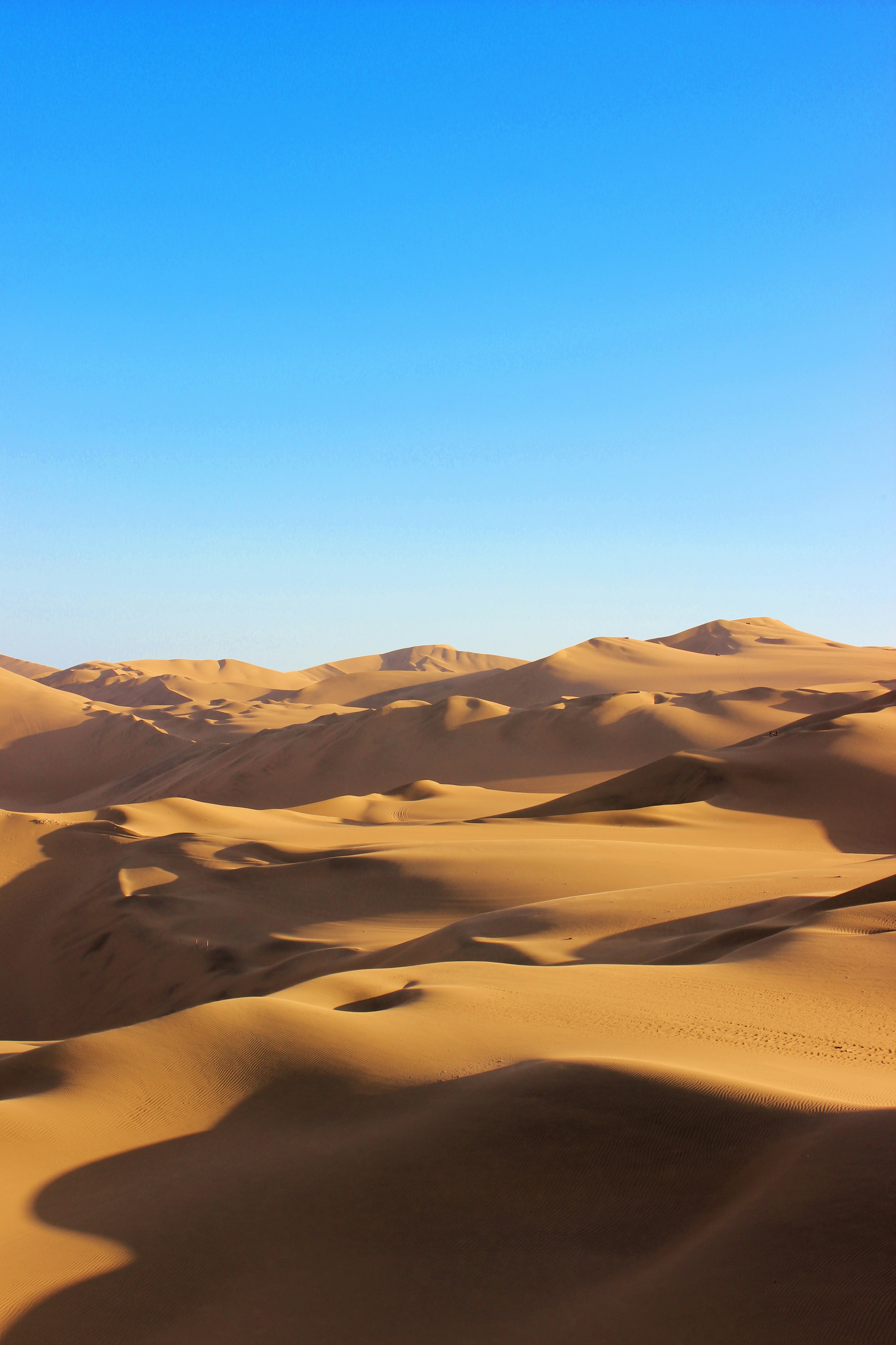 Huacachina sand dunes glowing golden under a deep blue sky, Ica Peru