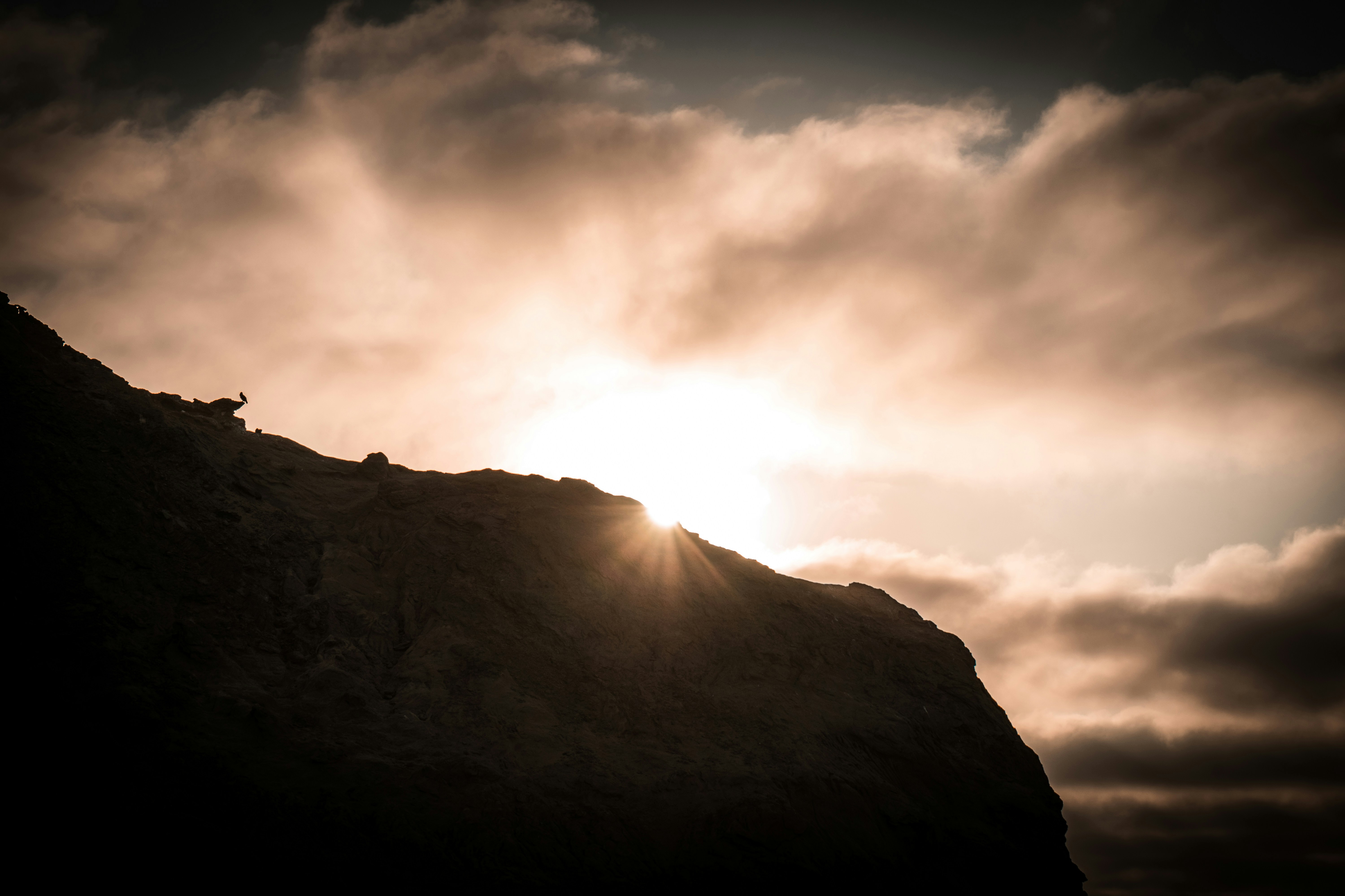Rocky headland silhouette with sun rays at sunset, Peruvian Pacific coast near Piura