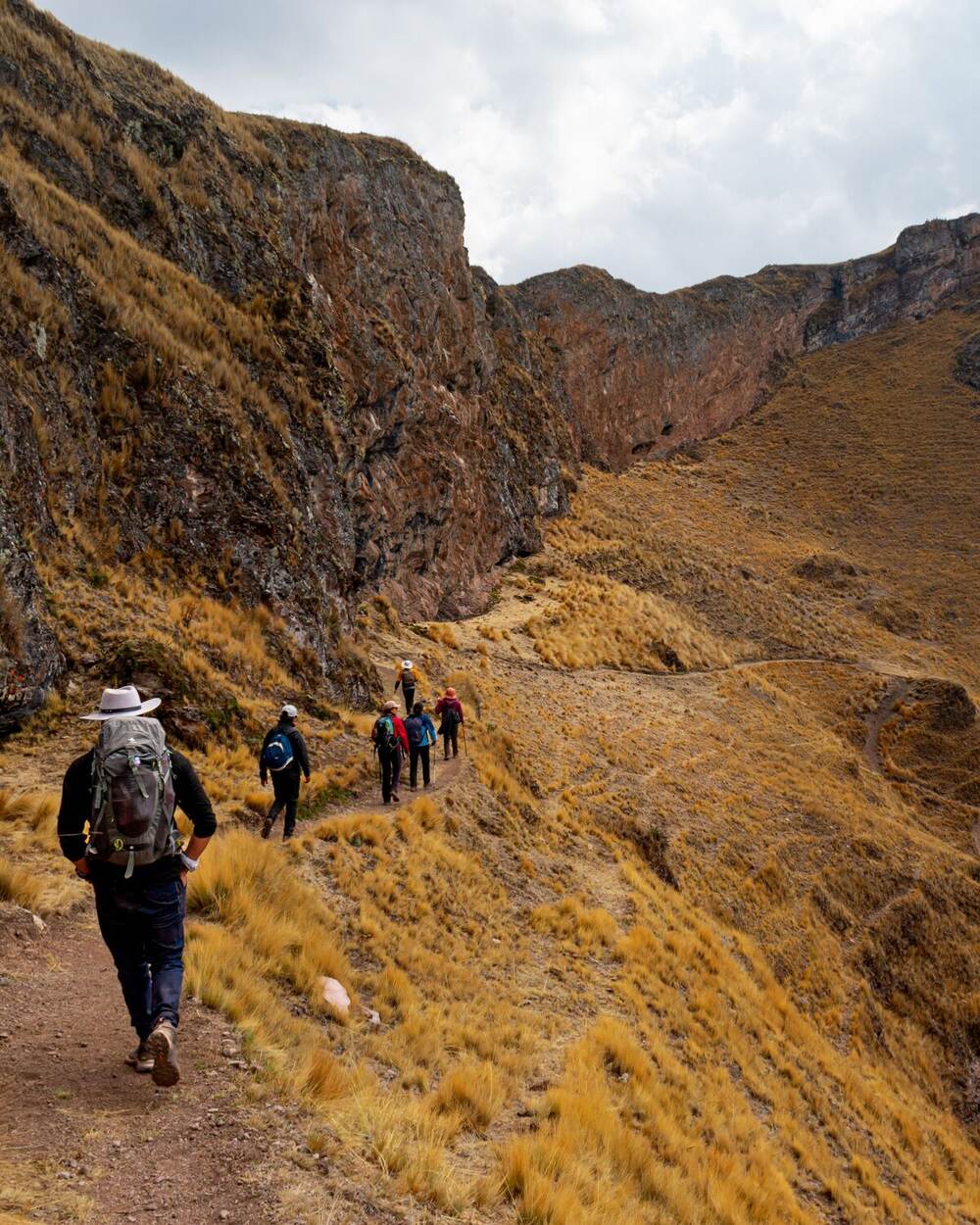 Hikers trekking a narrow Andean mountain trail near Ollantaytambo, Sacred Valley, Peru