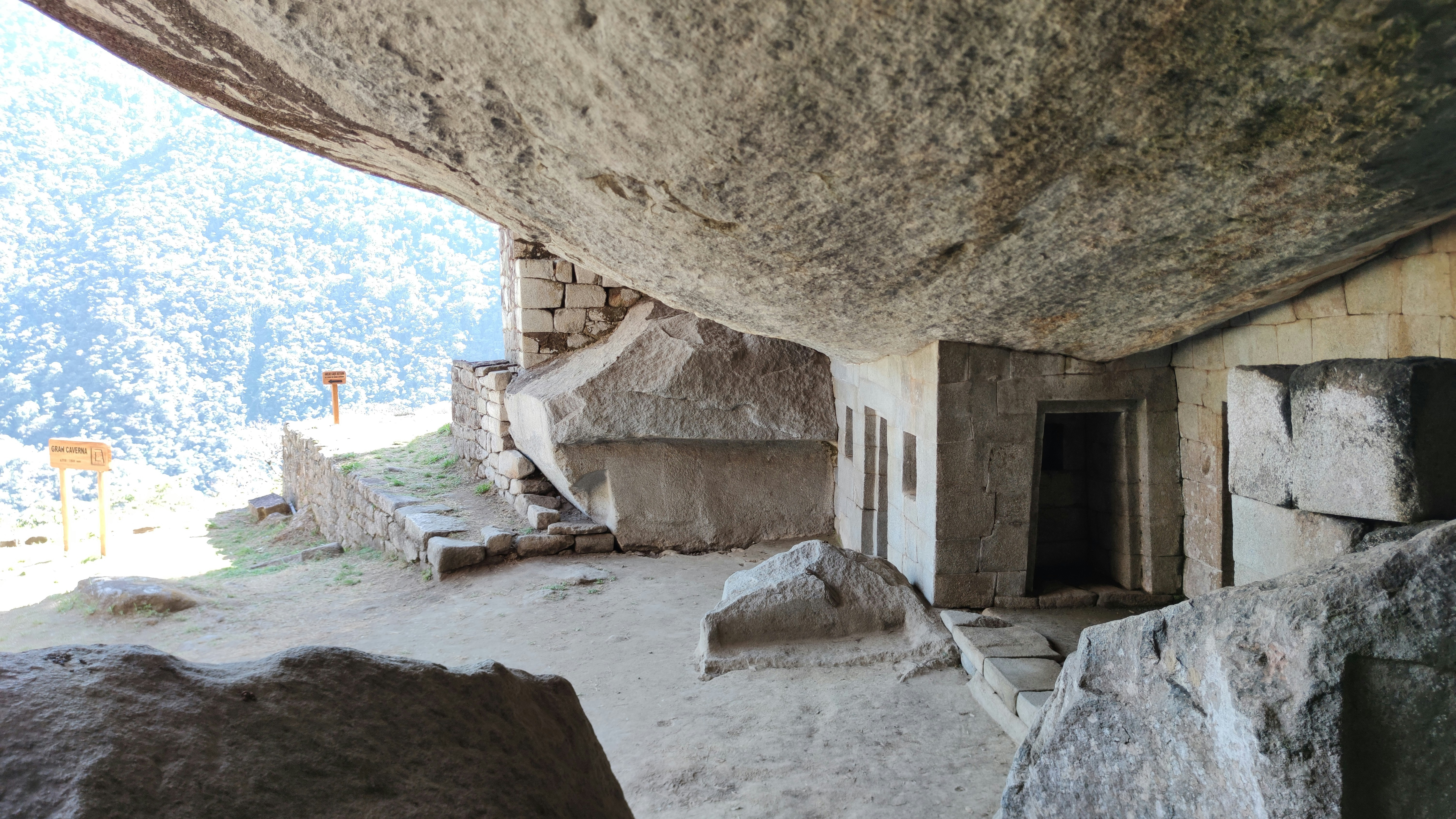 Ancient Inca stone chambers carved into a rocky overhang at Templo de la Luna, Cusco, Peru