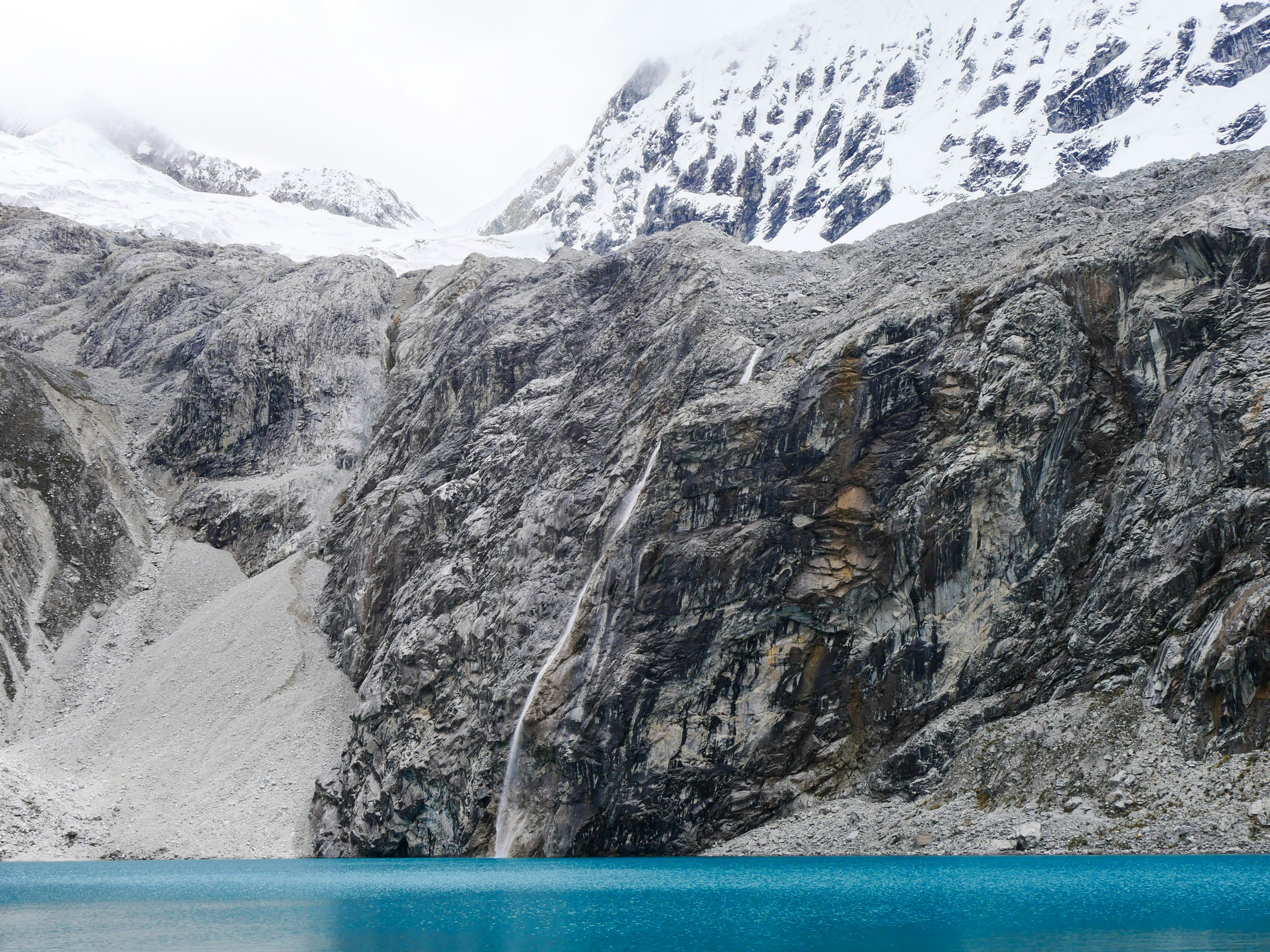Turquoise glacial waters of Laguna 69 below snow-capped Cordillera Blanca peaks, Huaraz, Peru