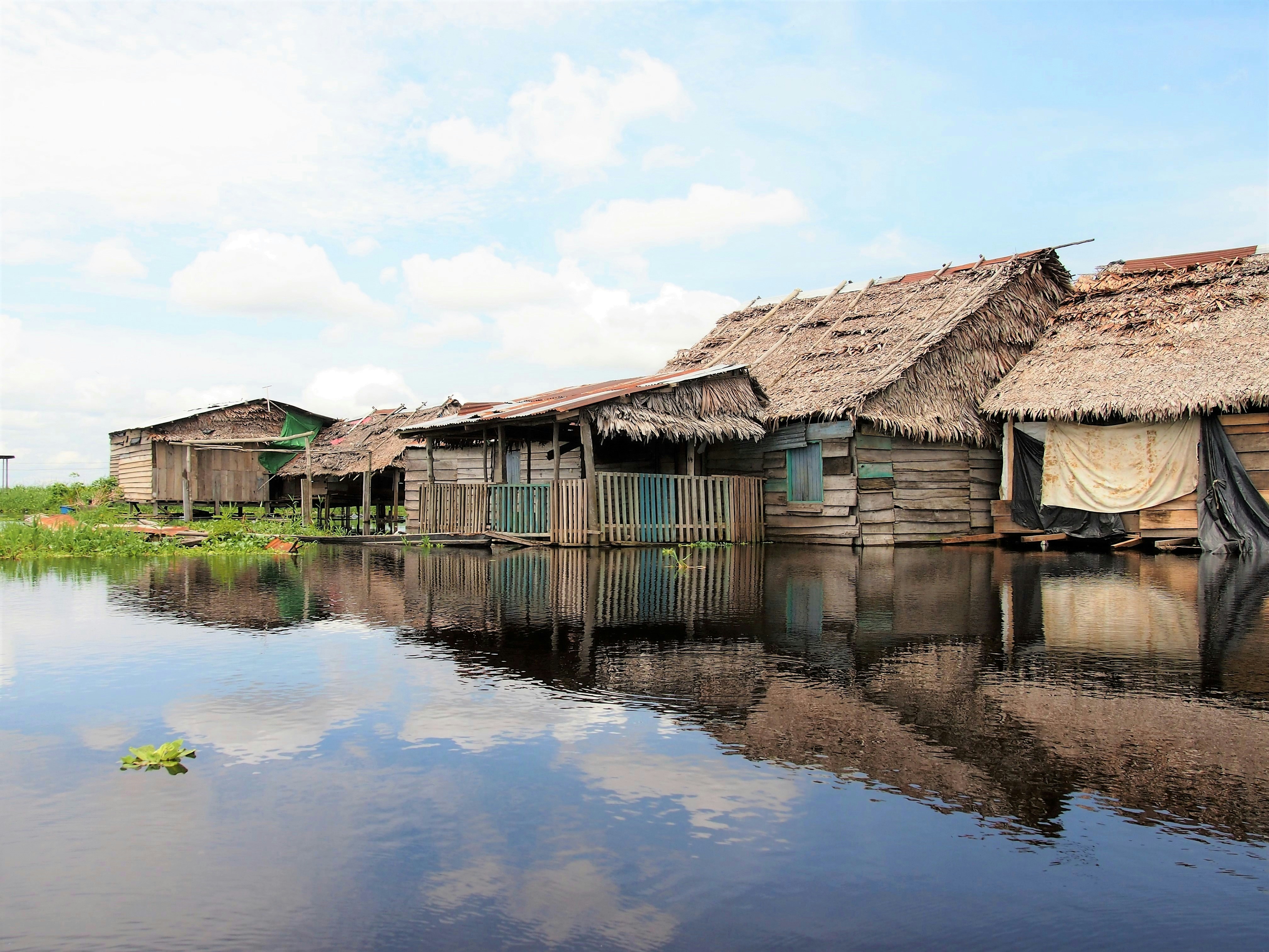 Stilted wooden houses reflected in still Amazon water at Belén, Iquitos, Peru