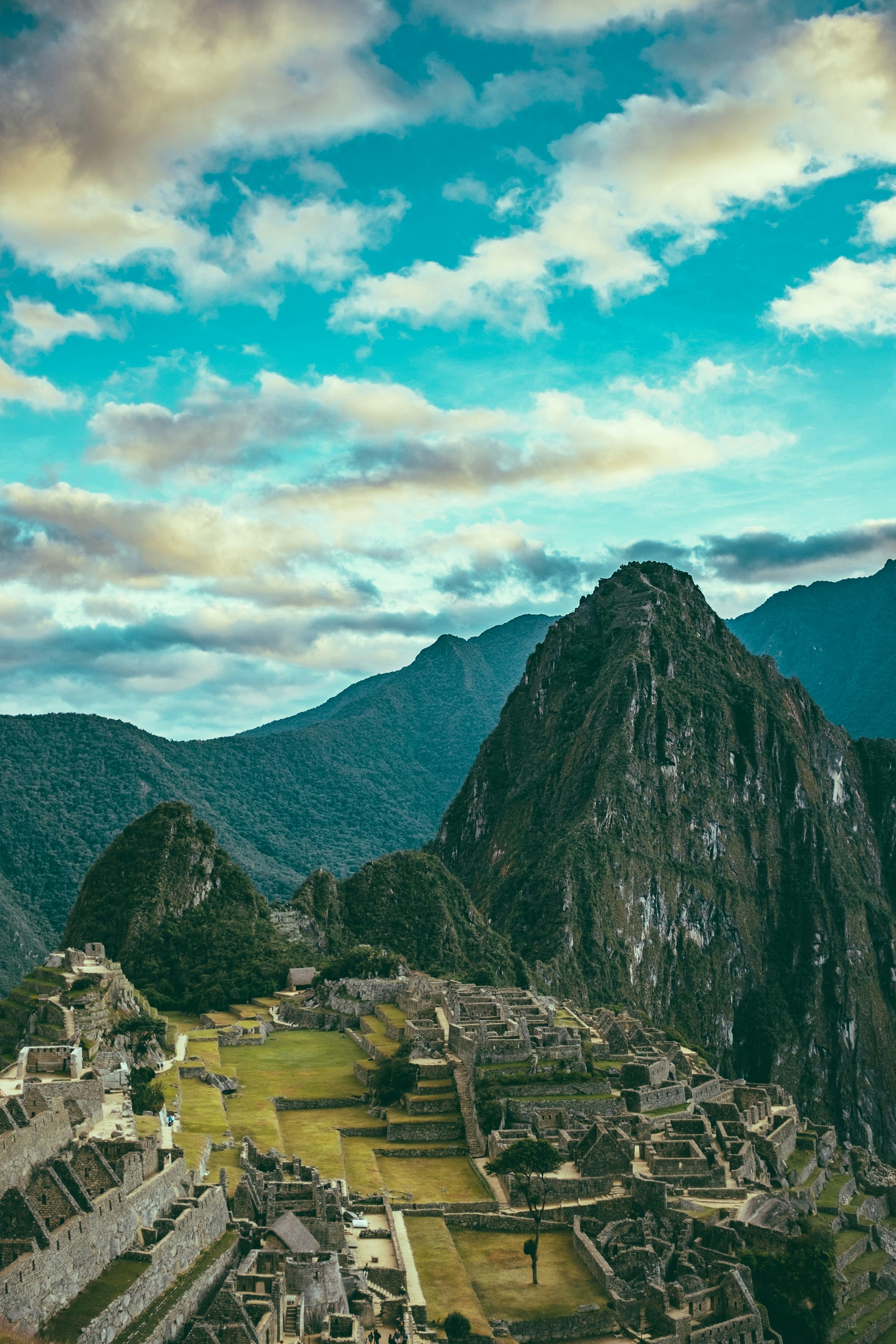 Aerial view of Machu Picchu ruins and Huayna Picchu peak under cloudy skies, Peru