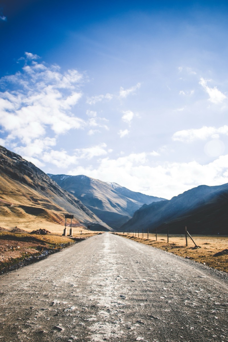 Empty paved road stretching into the Andean mountains near Cusco, Peru