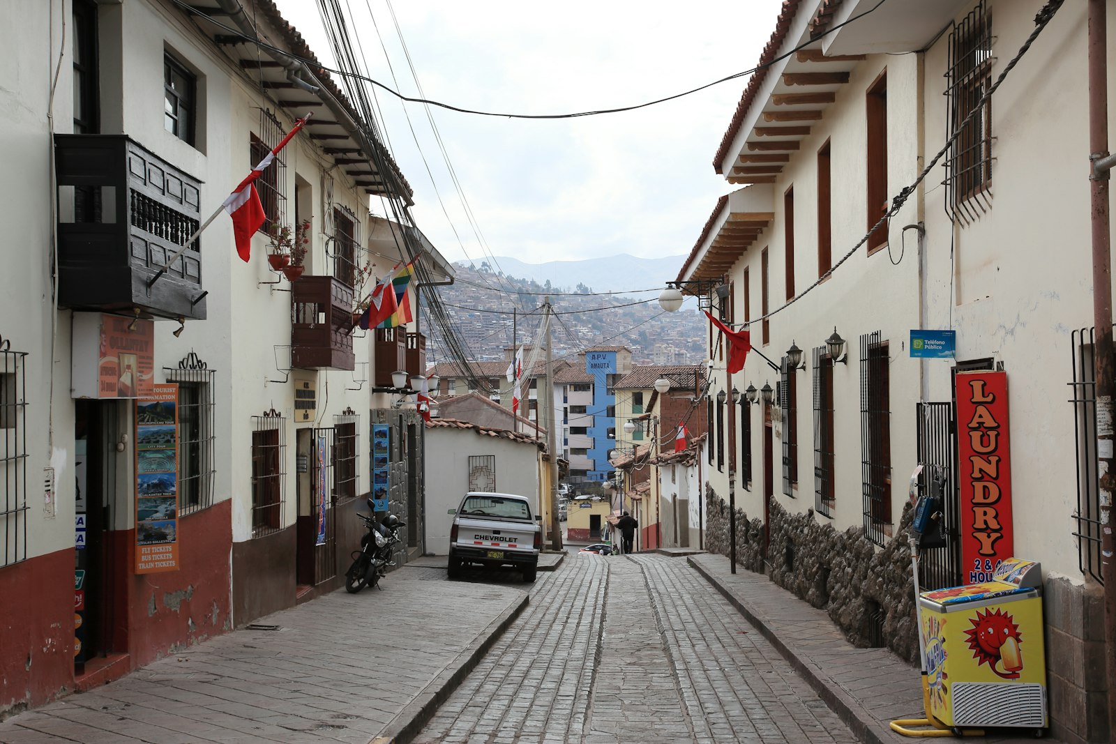 Cobblestone street in Cusco, Peru lined with colonial buildings and Peruvian flags