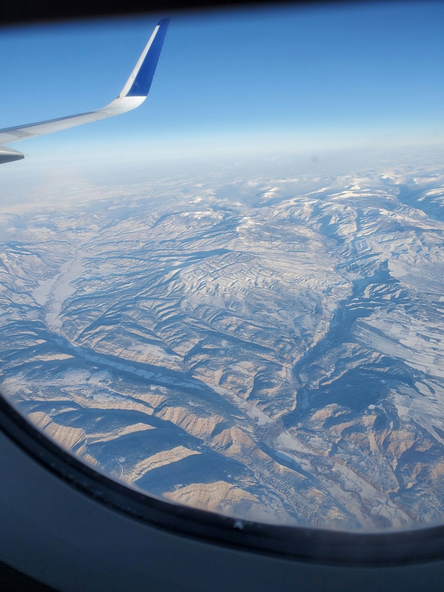 View from airplane window over snow-capped Andean mountain range, flying to Peru