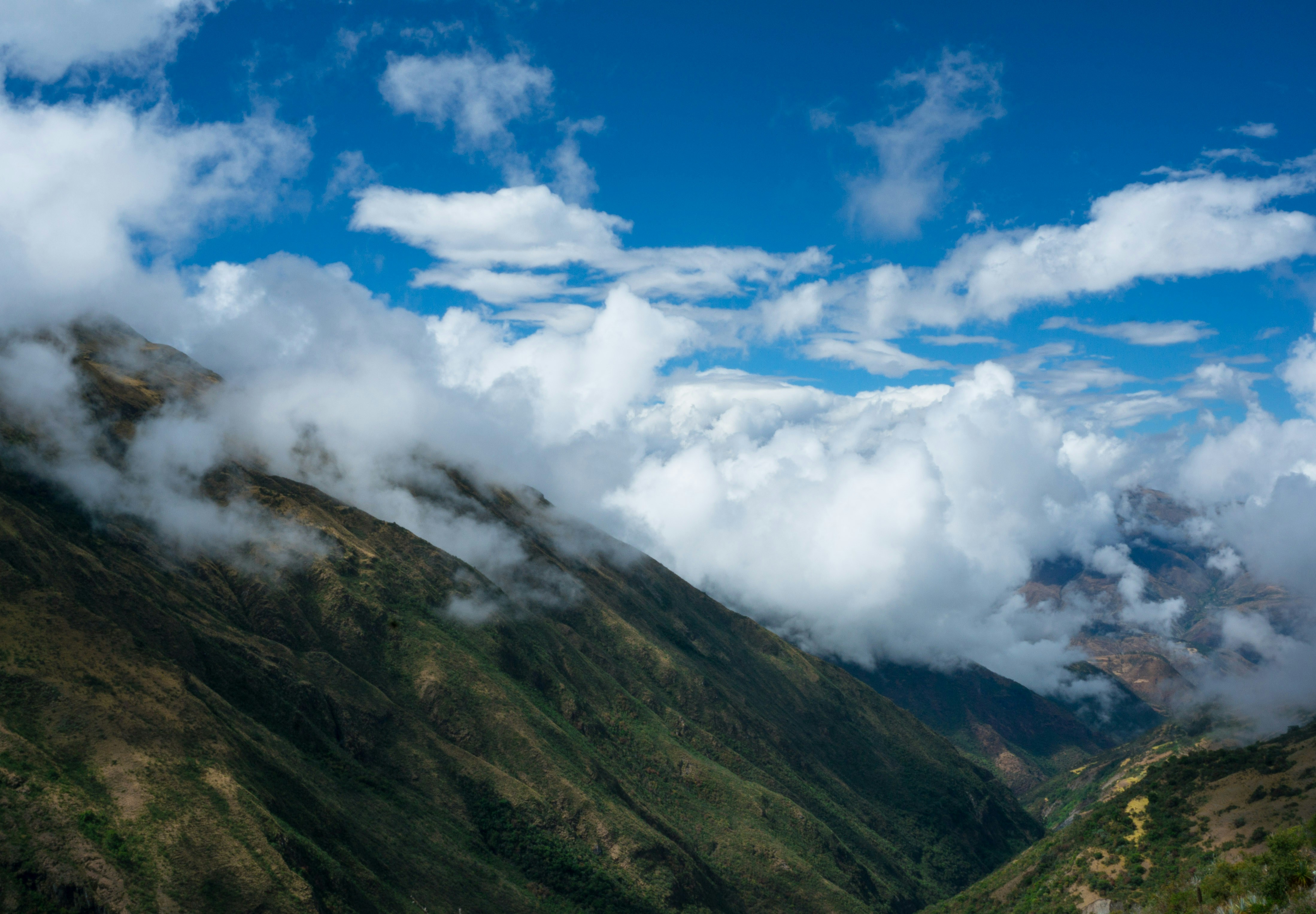 Andean mountain valley with white clouds and clear blue sky in the dry season, Peru