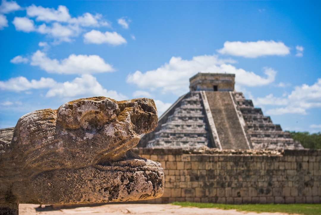 El Castillo pyramid at Chichen Itza, Mexico, with a carved serpent head in the foreground
