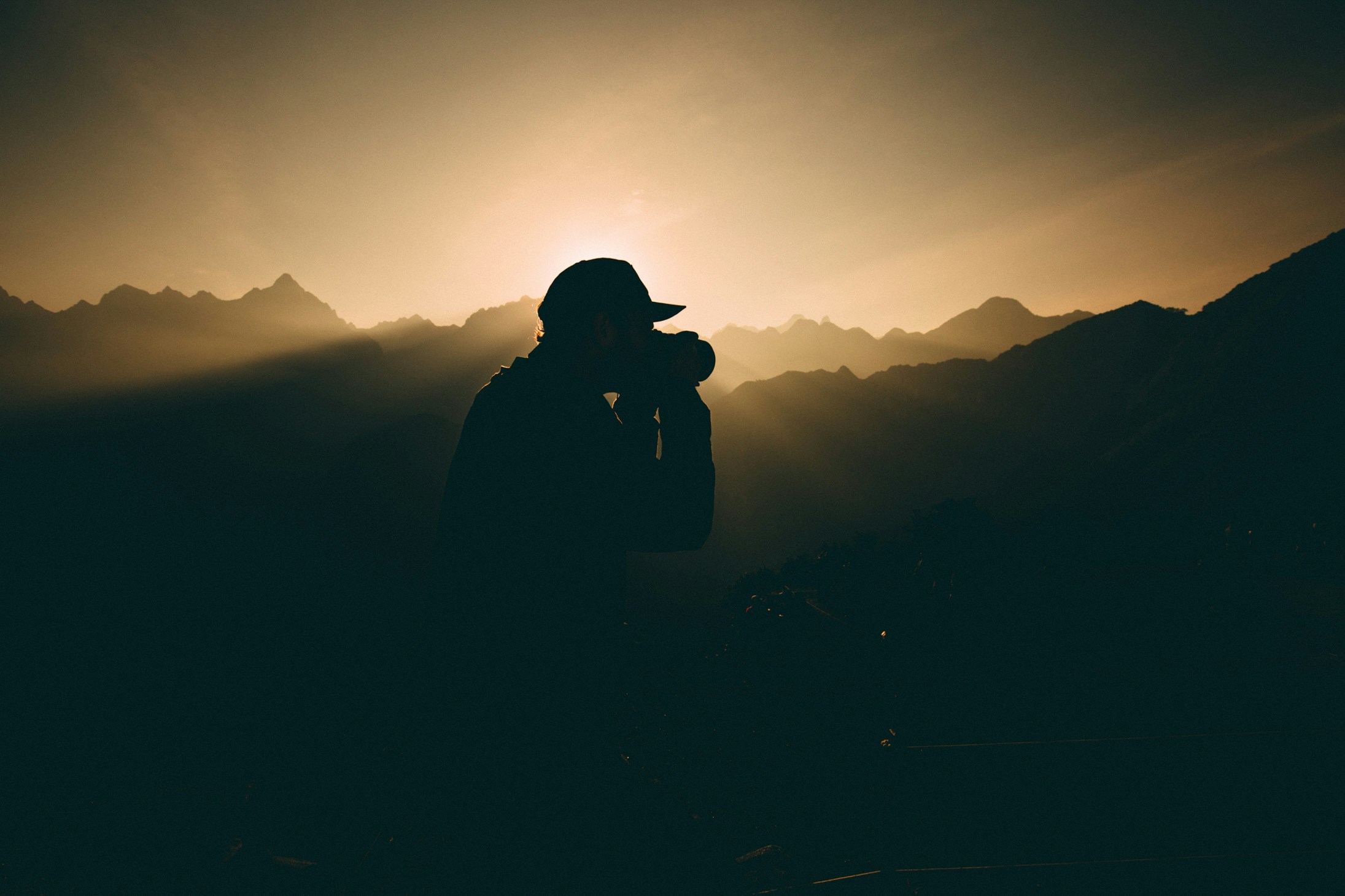 Hiker silhouette photographing mountain peaks at sunset on the Inca Trail, Peru