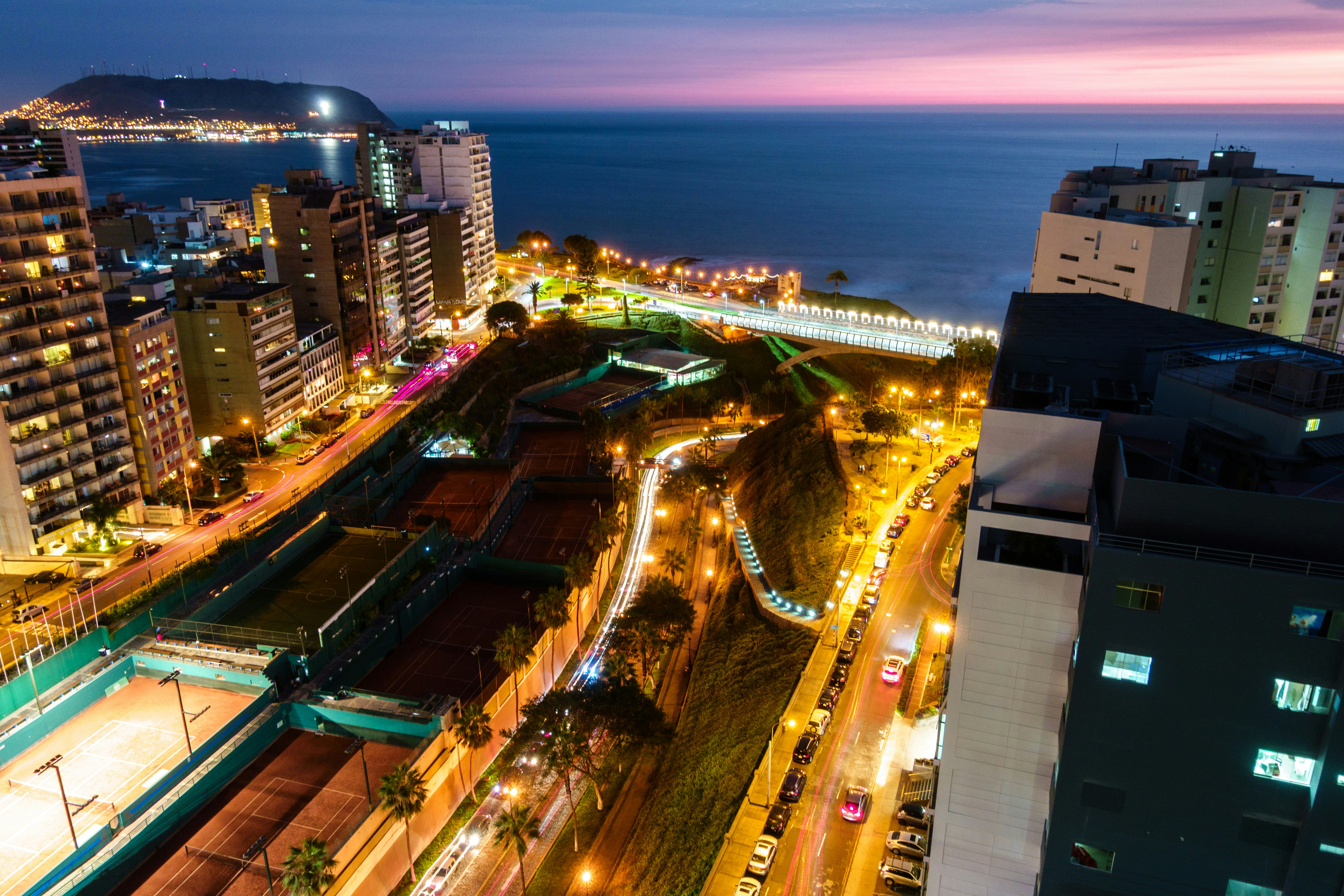 Lima Miraflores at night, city lights and Pacific Ocean horizon aerial view
