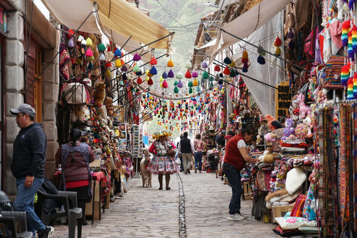 Colourful market stalls and local vendors on a cobblestone street in Pisac, Peru