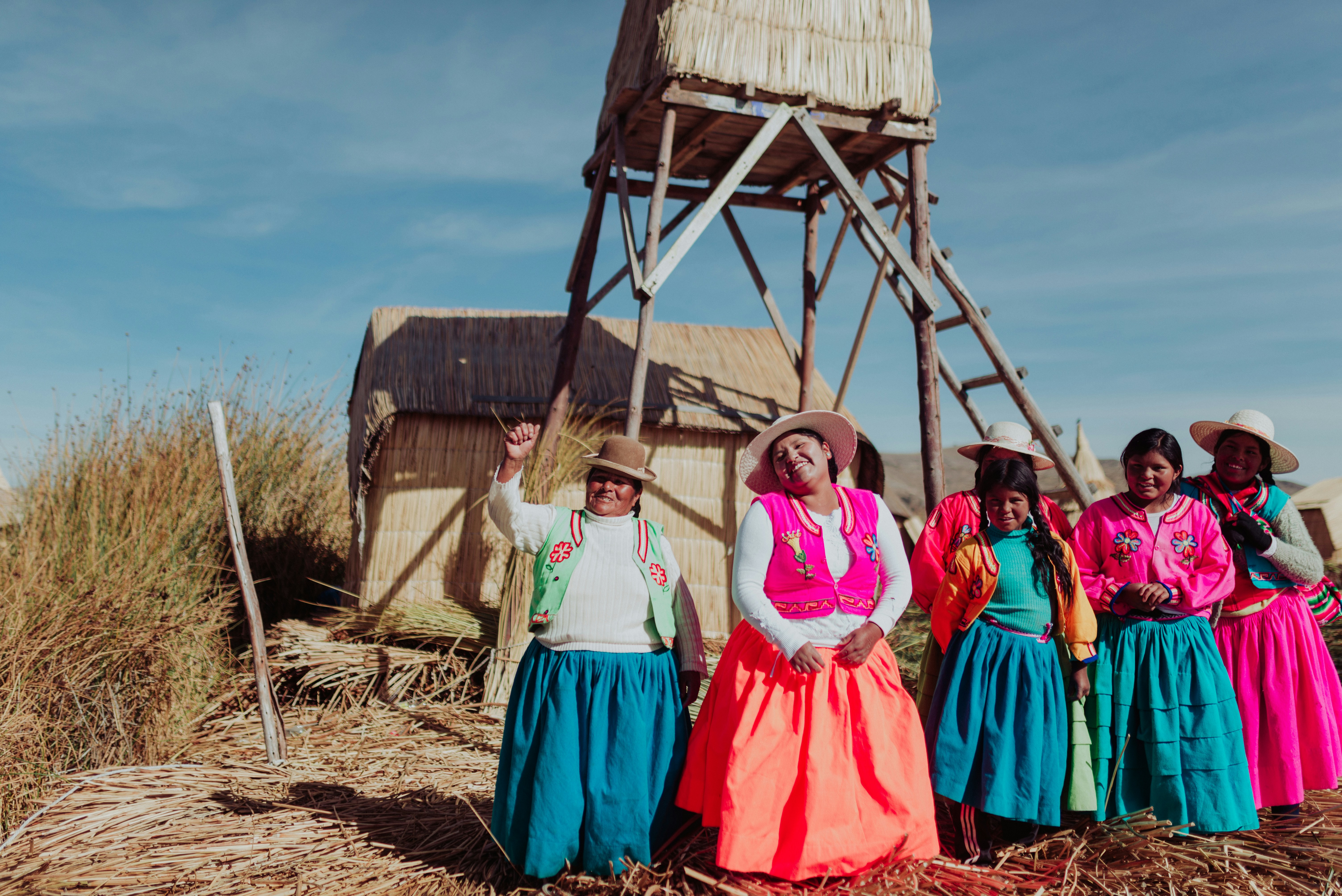 Uros women in traditional colourful dress on a reed island, Lake Titicaca, Puno, Peru