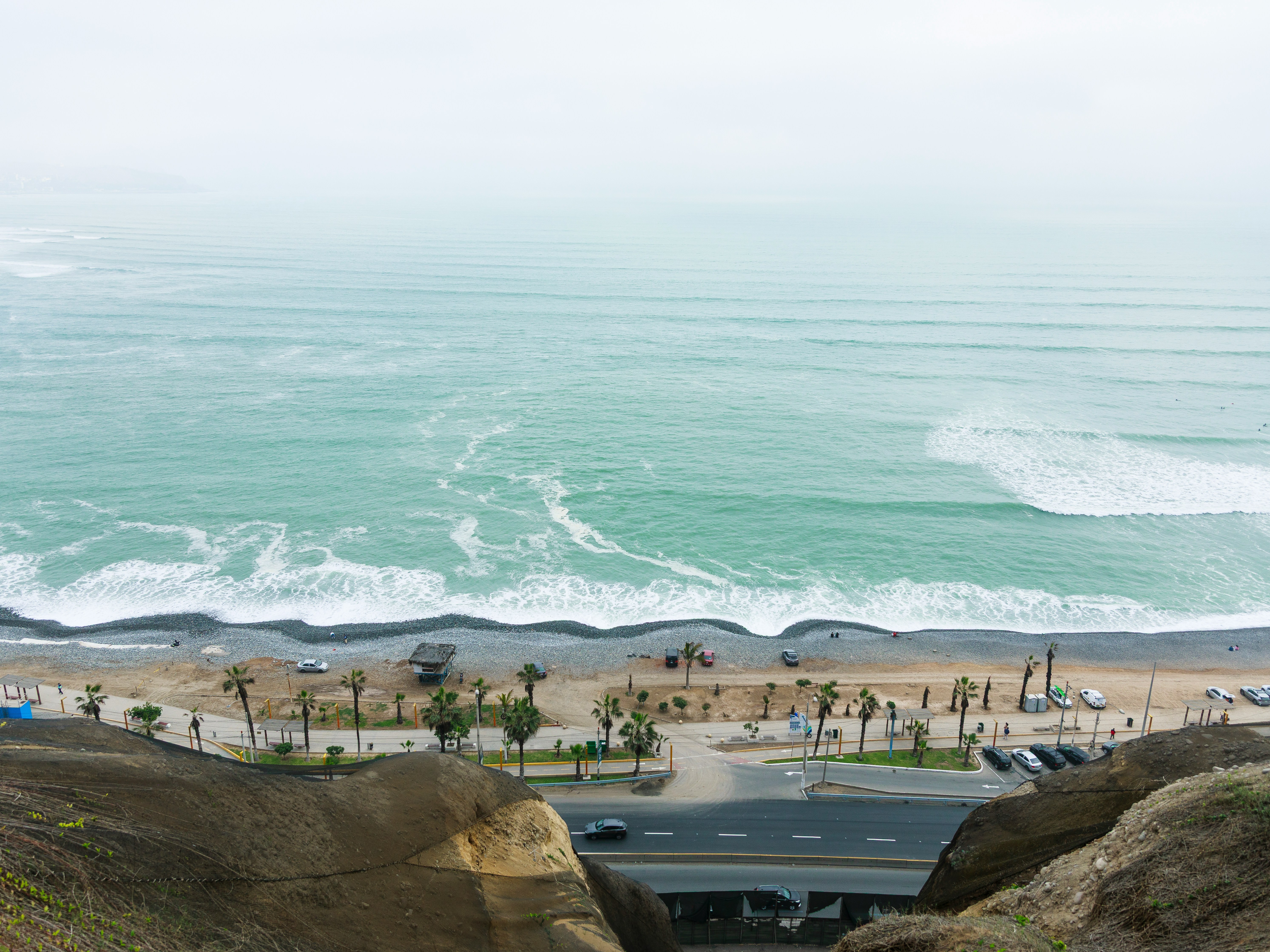 Waves breaking on a pebble beach with palm trees along the Peruvian Pacific coast