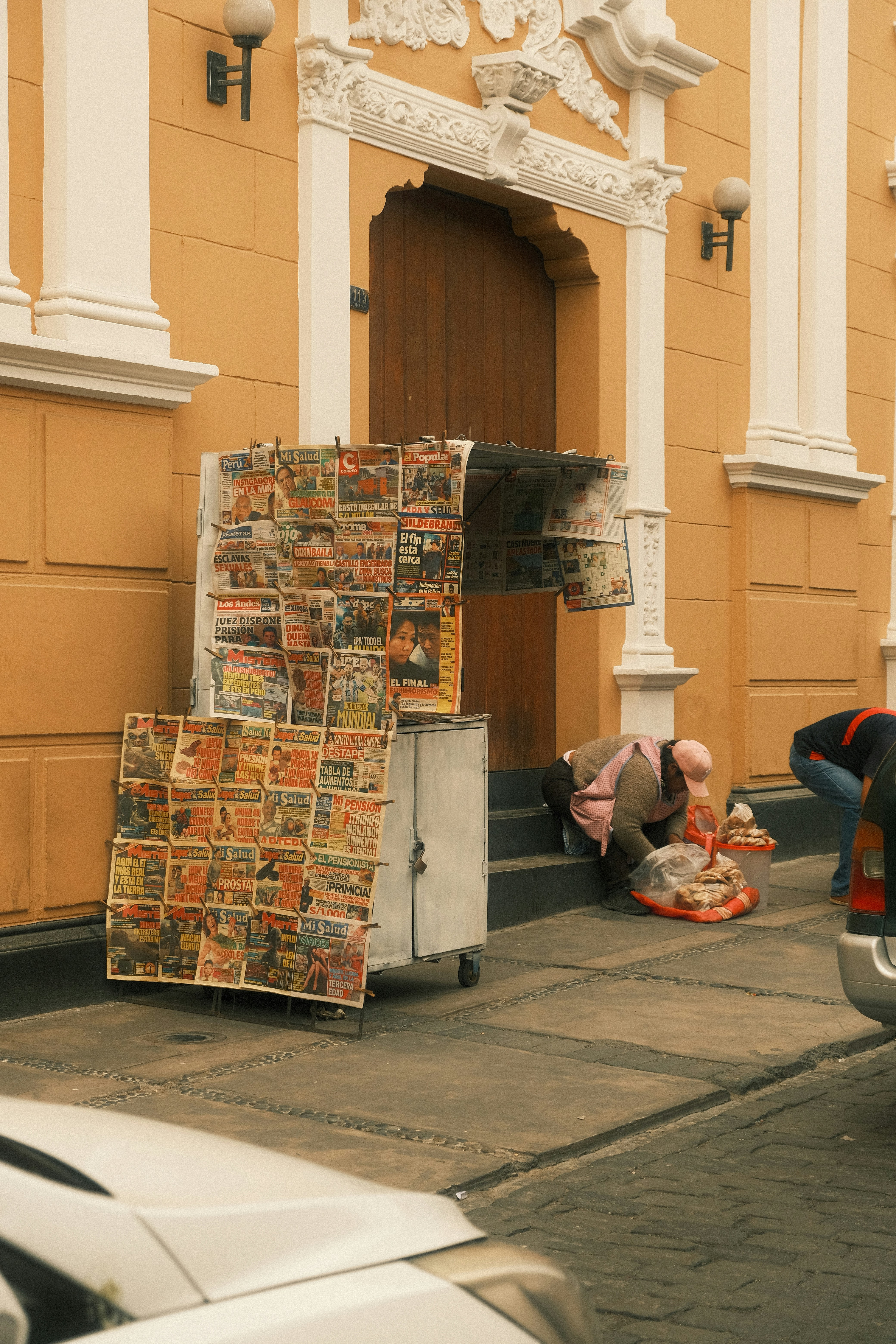 Arequipa colonial street with yellow building and white stone trim, newspaper vendor outside, Peru